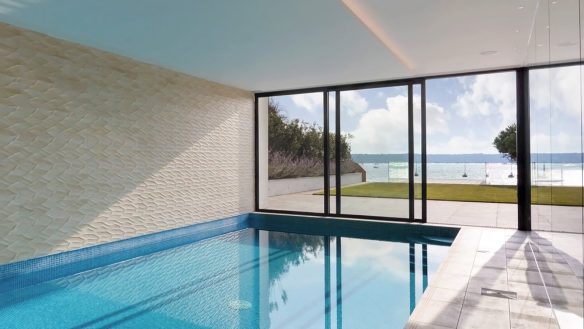 interior swimming pool with glass sliding roofs leading to back garden with sea views