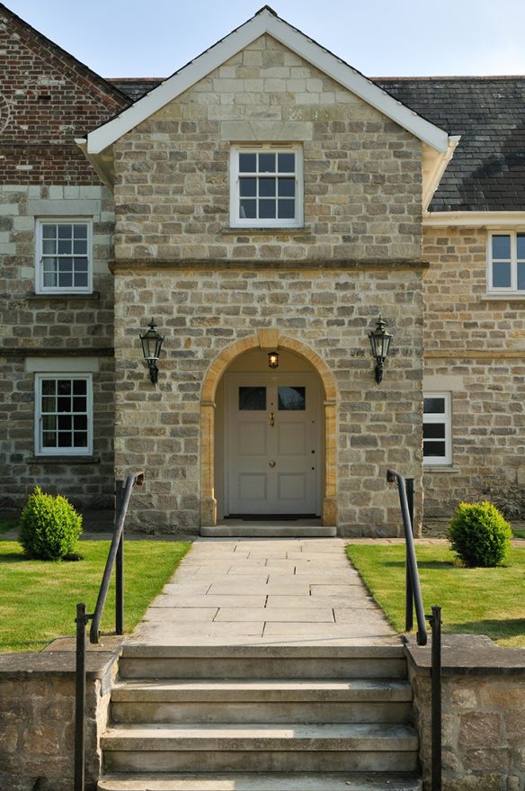 detail view of house with steps up to path leading to stone porch with curved arch