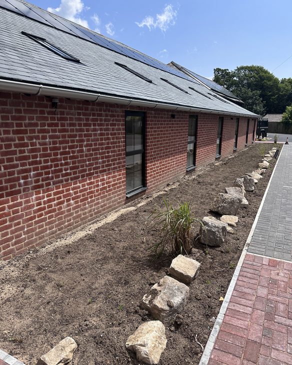 large single story red brick building with solar panels on the grey tiled roof