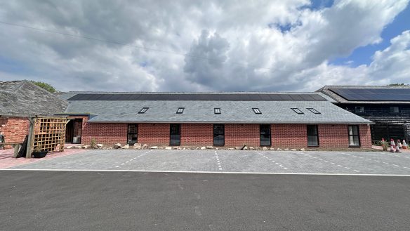 red brick single storey building with car parking spaces in front