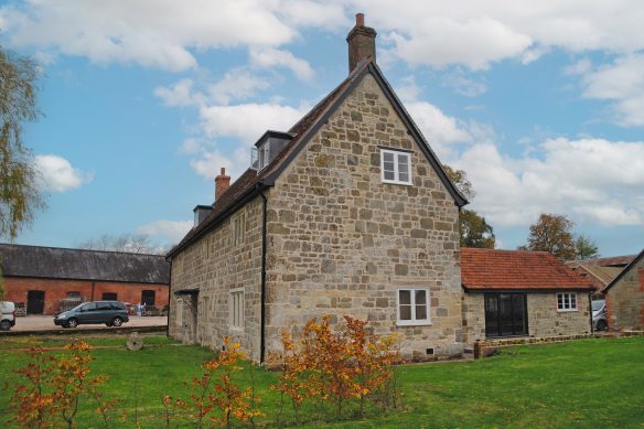 side view of stone detached house with outbuildings