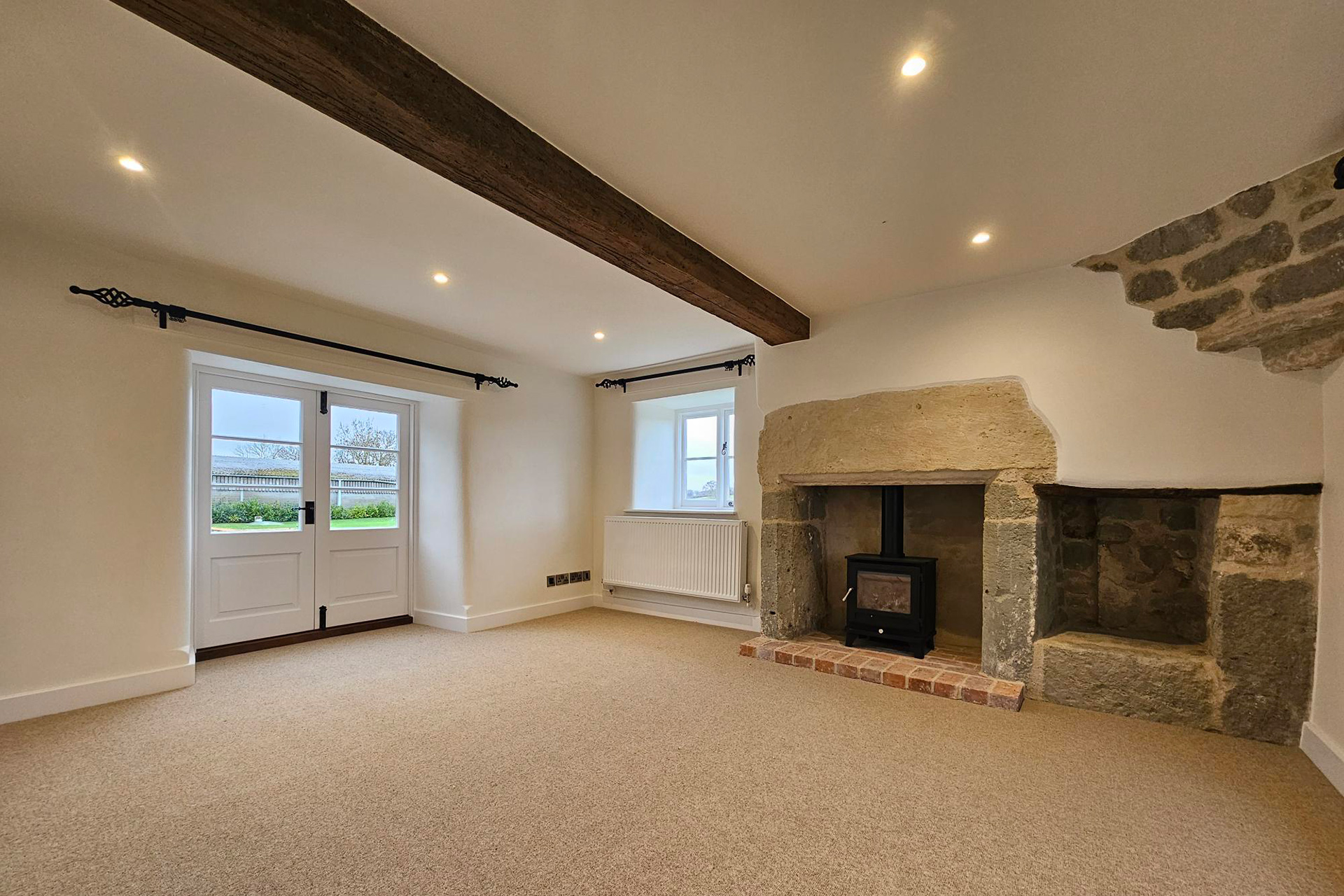 living room with wood burner fireplace with stone surround