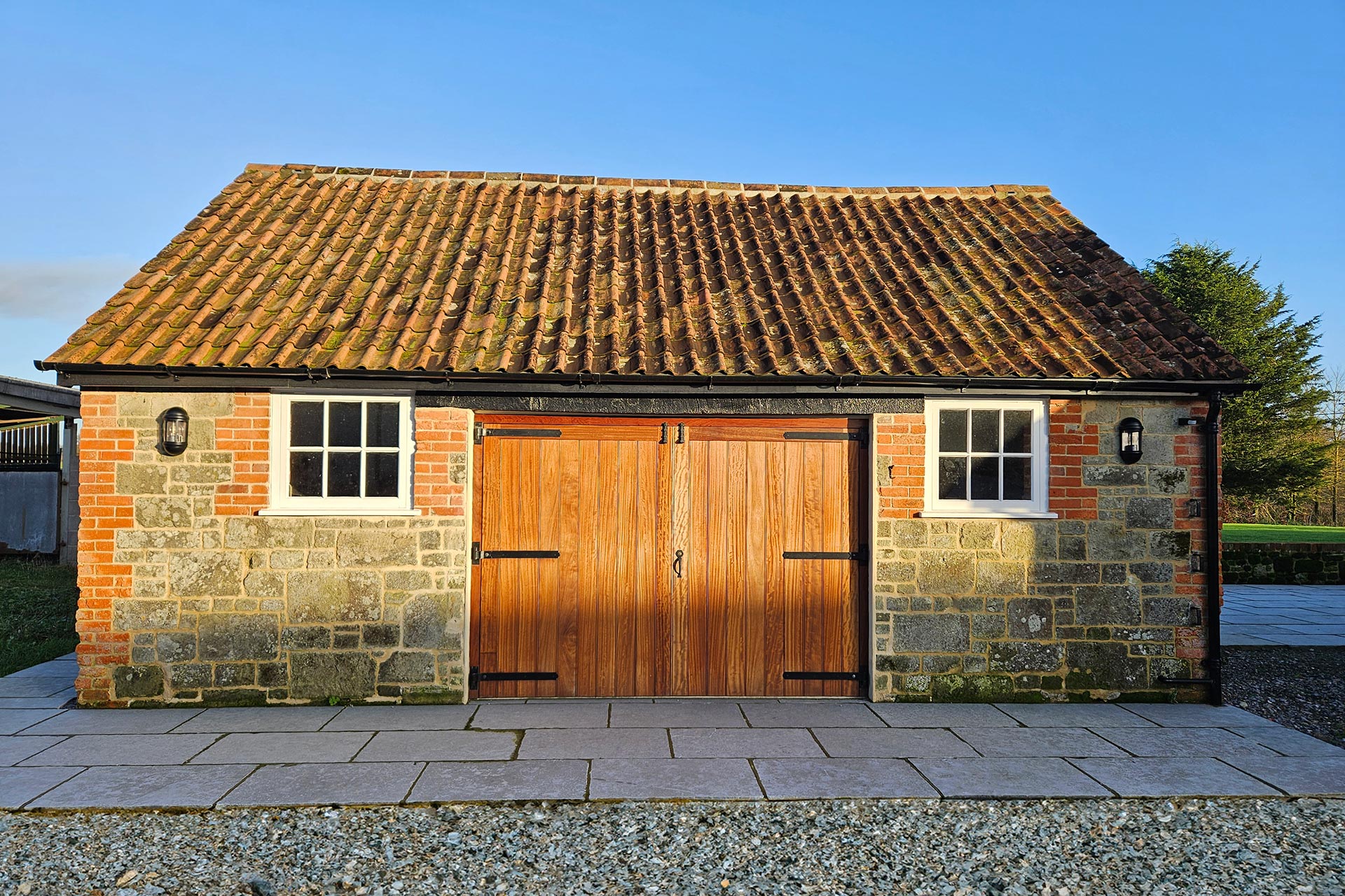 stone garage with double wooden doors and red tiled roof
