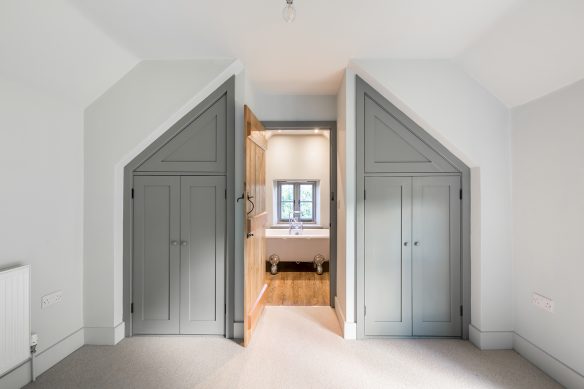 bedroom with fitted wardrobes and door leading to en-suite with roll-top bath