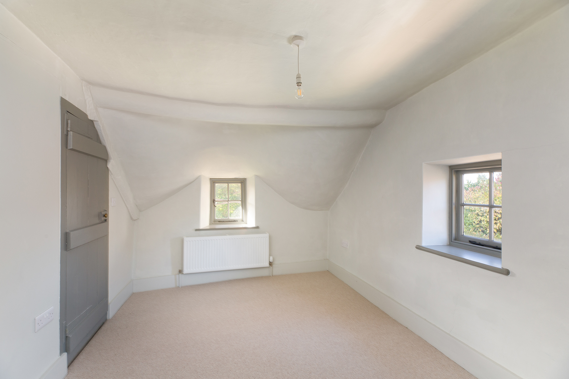 after photo of bedroom with slanted ceiling and traditional windows