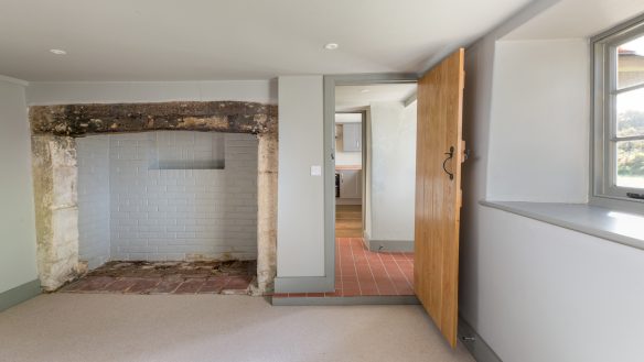 living area with large open fireplace and door leading to hallway and kitchen