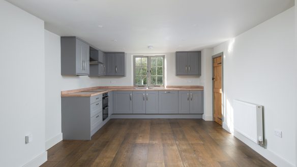 large modern kitchen area with grey units and wooden work surface