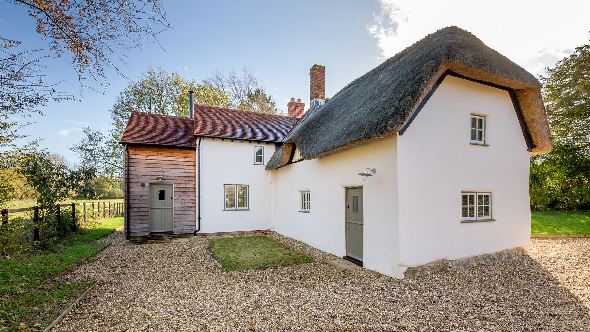 rear view of detached large cottage with thatched roof