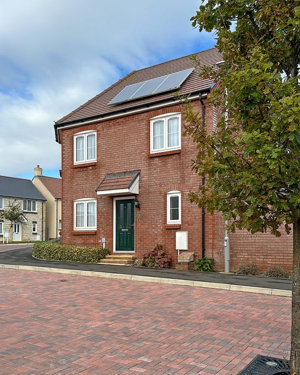 red brick house with solar panels on roof and red brick road in front