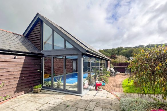 swimming pool house with large windows in garden