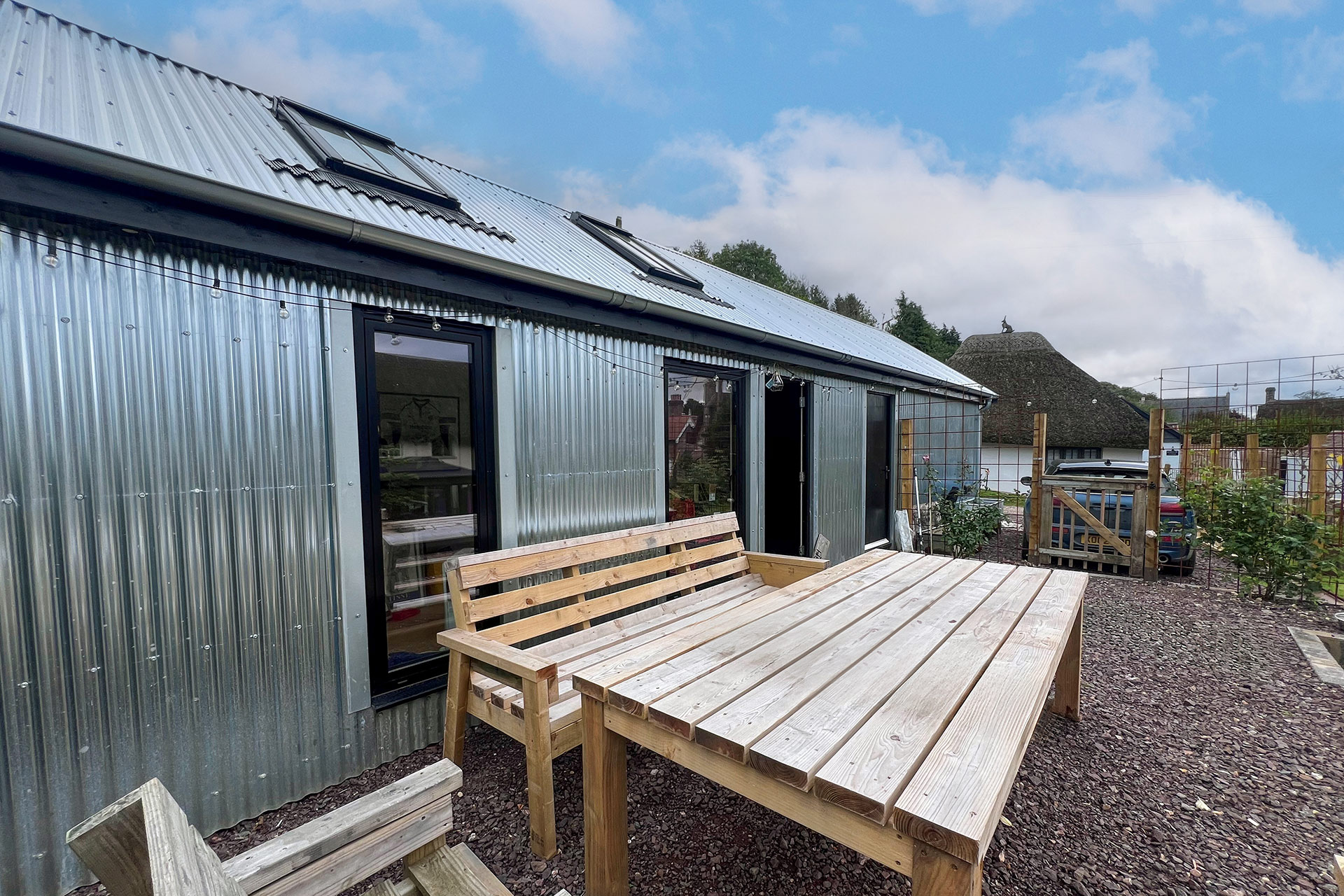 modern corrugated annex in garden with table and benches outside